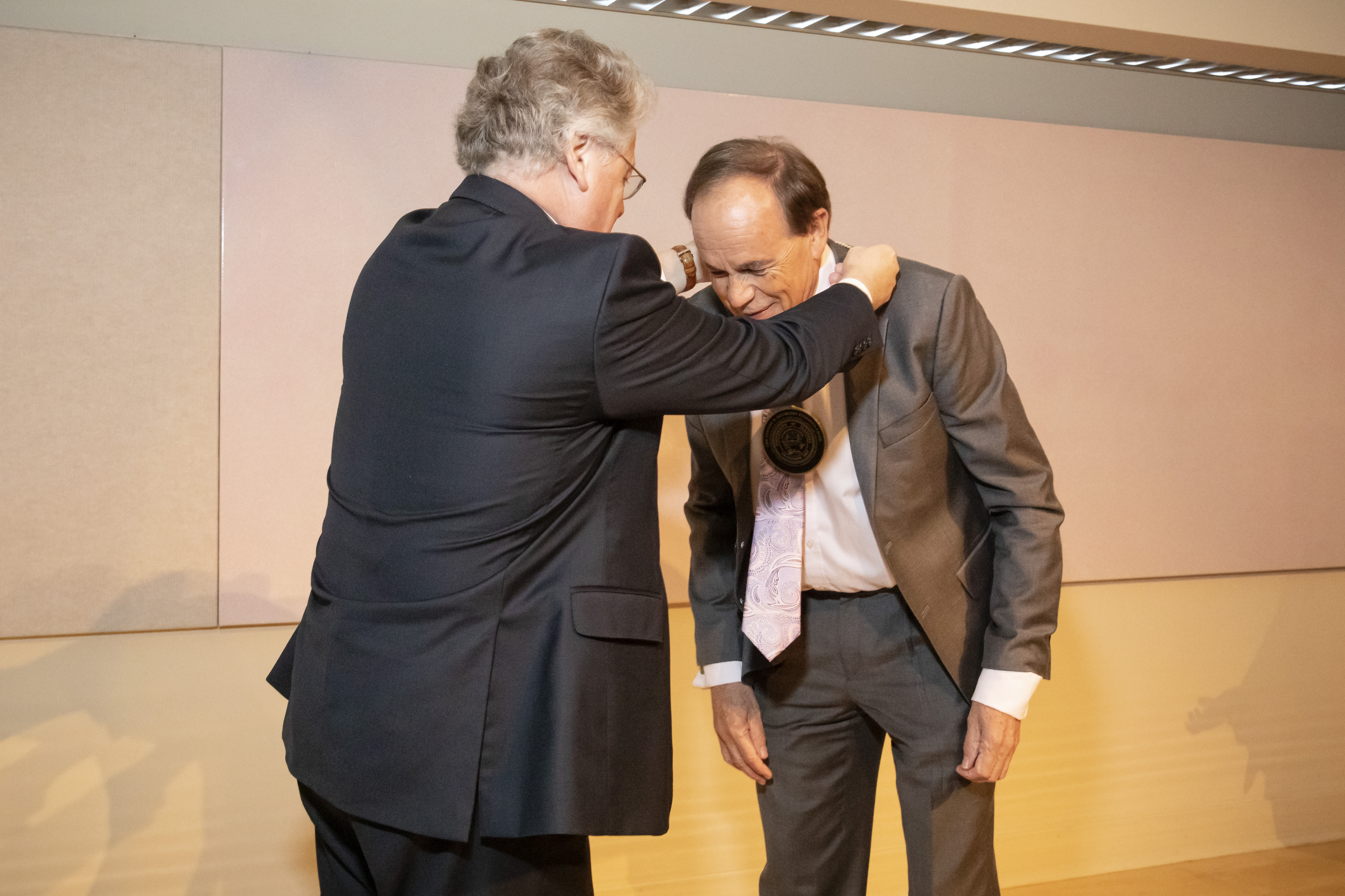 The provost places a medallion around Stephen Long's neck. 